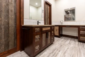 Custom bathroom vanity with dark wood frame and rustic reclaimed wood tilt-out cabinet door, designed for hidden storage. The piece blends modern craftsmanship with natural textures for a functional and stylish finish.